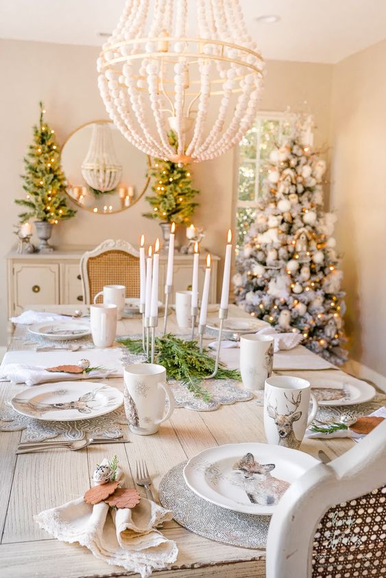 a refined woodland glam Christmas tablescape with silver placemats, printed plates and mugs, wood pinecones and bells plus a modern candelabra is wow