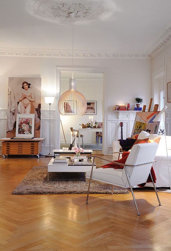 a bold and chic living room with catchy and pretty molding, with a refined ceiling medallion, white modern and vintage furniture and bold books and accessories
