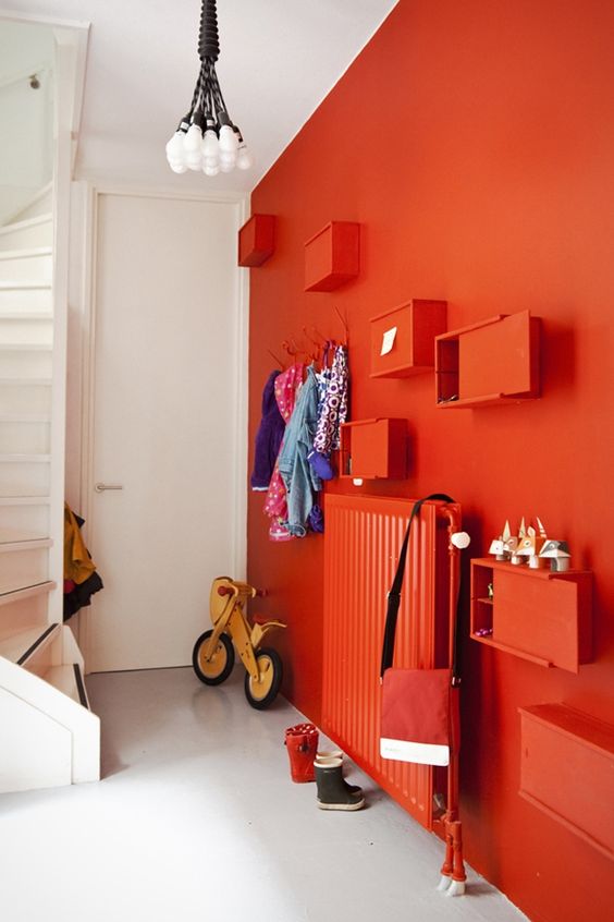 a bold red wall with matching box shelves and a radiator that create a cohesive look as they match in color and look modern
