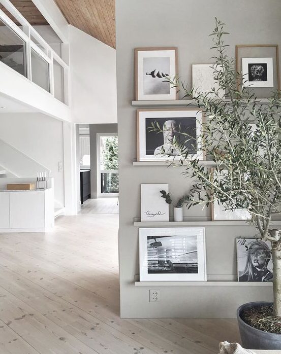 a chic contemporary gallery wall with grey ledges on a matching wall, black and white photos in mismatching frames