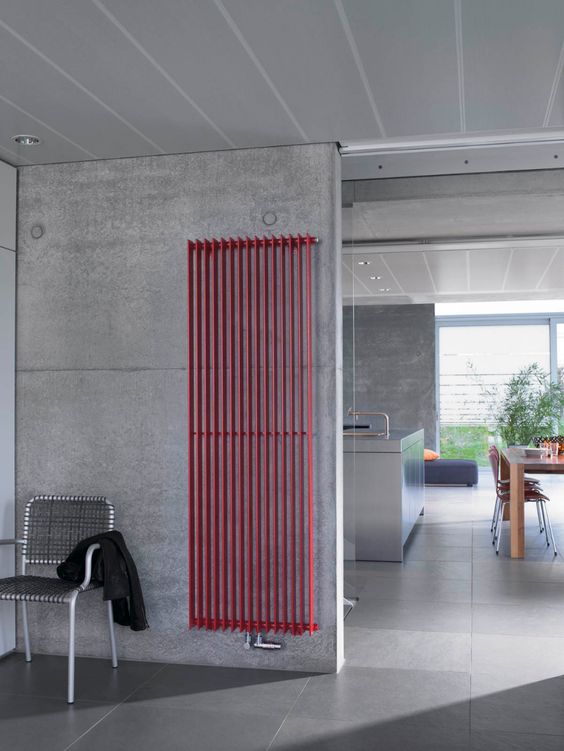 a contemporary industrial space of concrete and with concrete tiles plus a hot red radiator on the wall for a bold touch of color