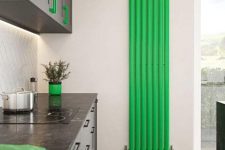 a contemporary kitchen with black and grephite grey cabinetry, a neon green radiator on the wall and matching accessories