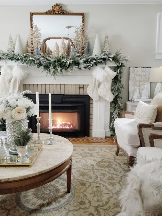 a fab winter wonderland Christmas space with faux fur stockings, an evergreen garland, mini trees on the mantel, neutral pillows and furniture