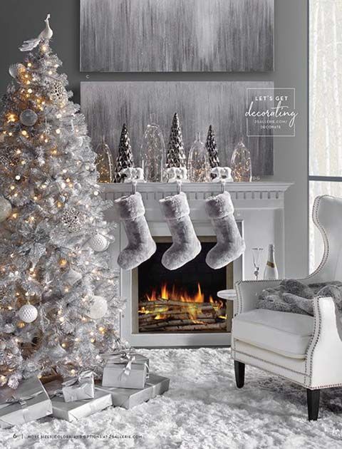a lovely winter wonderland space with a silver Christmas tree with white ornaments and lights, white faux fur stockings and mini trees on the mantel