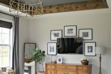 a modern farmhouse bedroom featuring a grey ceiling with stained rustic crown molding, a catchy chandelier, a mini gallery wall and vintage and modern furniture