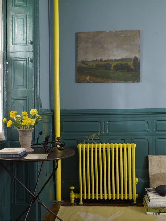 a moody vintage-inspired space with blue walls and dark green wainscoting, a neon yellow radiator and a tube, bold blooms