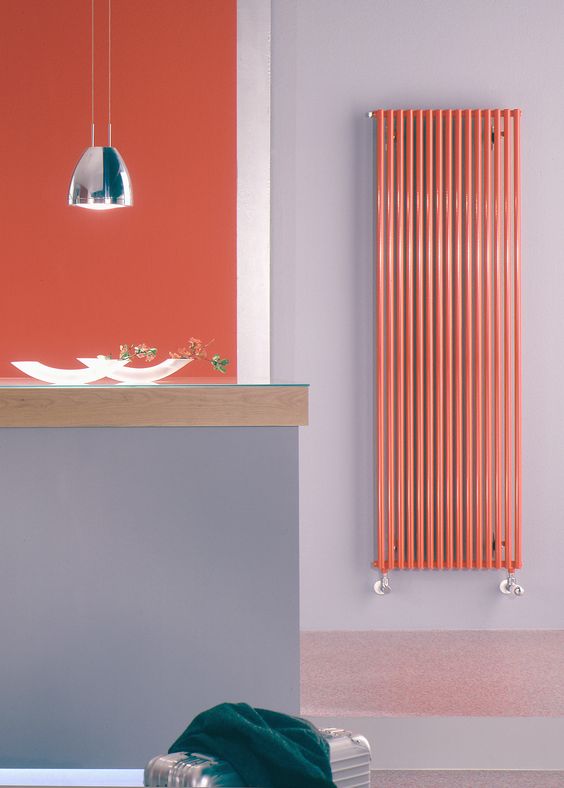 a neutral grey space with an orange accent wall and a vertical wall radiator that matches in color and gives a bold touch to the space