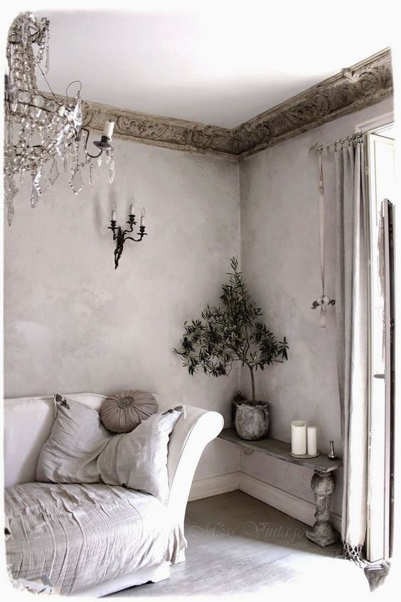 a neutral shabby chic space with a strong French feel, with vintage weathered stained molding and a crystal chandelier