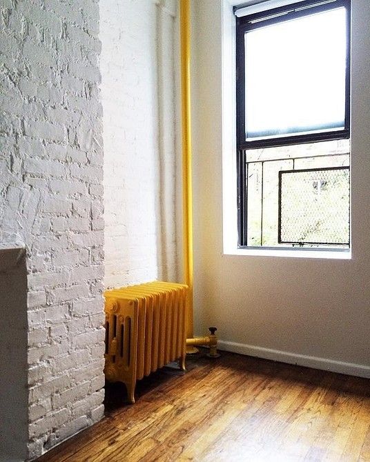a neutral space with a cool gold-touched floor and a bold yellow vintage radiator for a bold accent in the space