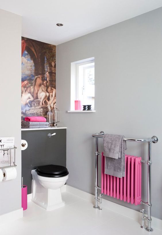 a pretty bathroom with a grey wall, a bold artwork, a vintage toilet, a bold pink radiator and some accessories that echo with it