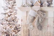 a pretty winter wonderland Christmas space with a flocked Christmas tree with lights, faux fur stockings and a stool, mini houses on the mantel