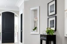 a refined modern entryway with dove grey walls, white molding including crown molding, black and dark touches for a bold contrast is a chic space