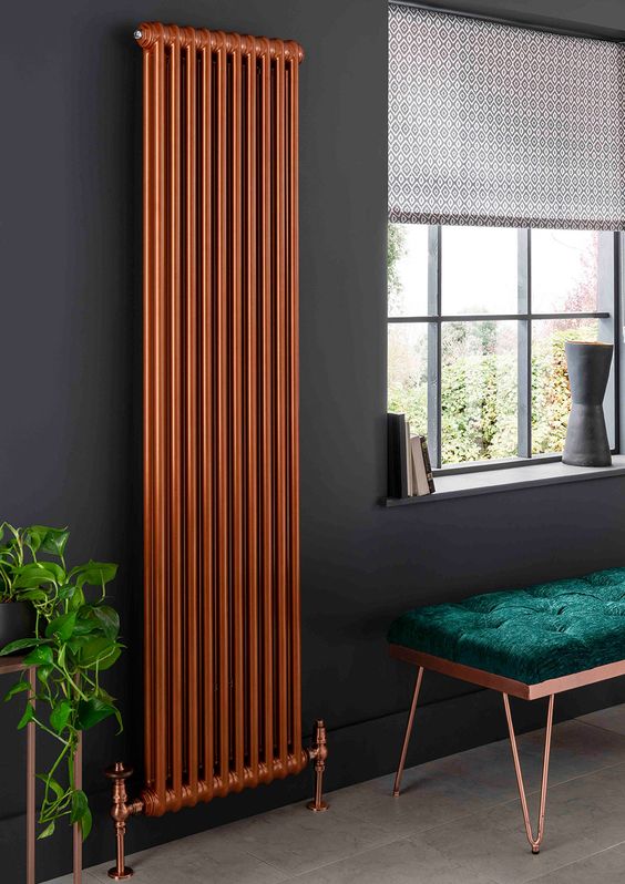 a refined moody space with black walls, an emerald and copper bench, a matching copper radiator, a printed shade is a bold nook