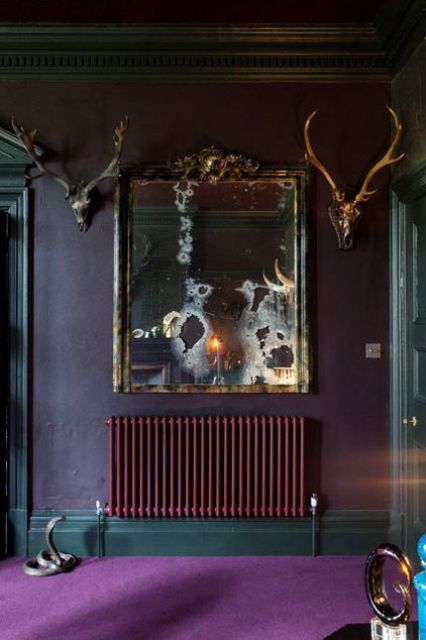 a sophisticated moody space with deep purple walls, a matching radiatoer, touches of dark green and antlers on the wall