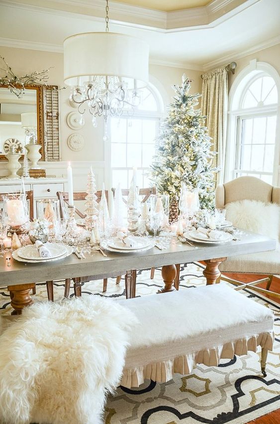a winter wonderland Christmas tablescape with lots of candles, elegant white porcelain and faux fur around