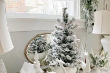 lovely winter wonderland decor with deer figurines, a church, bottle brush and a usual flocked Christmas tree in a super bowl is very chic