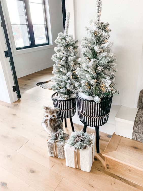 winter wonderland Christmas decor - potted flocked trees with lights, gift boxes with pinecones and a faux owl is amazing