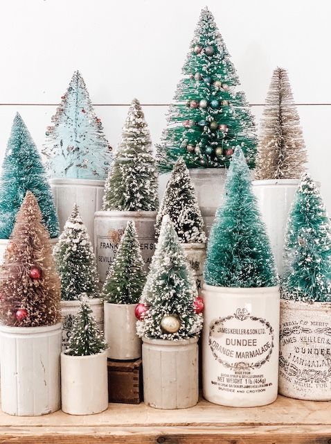 a beautiful arrangement of bottle brush Christmas trees with mini ornaments placed into planters and pots is cool