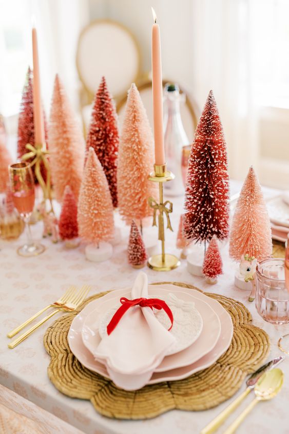 a bold holiday table with red and pink bottle brush trees, pink candles, woven placemats and pink porcelain