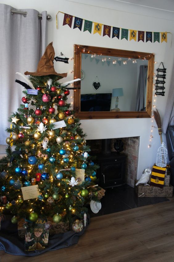 a colorful Christmas tree decorated with bold ornaments, lights, stars, letters and a Sorting Hat tree topper is wow