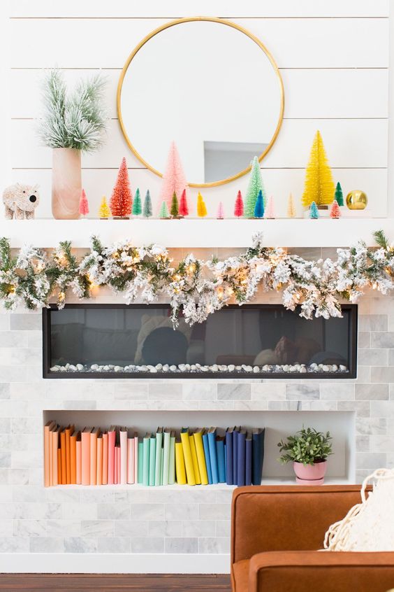 a bold Christmas mantel with colorful bottle brush Christmas trees, a snowy evergreen garland with lights