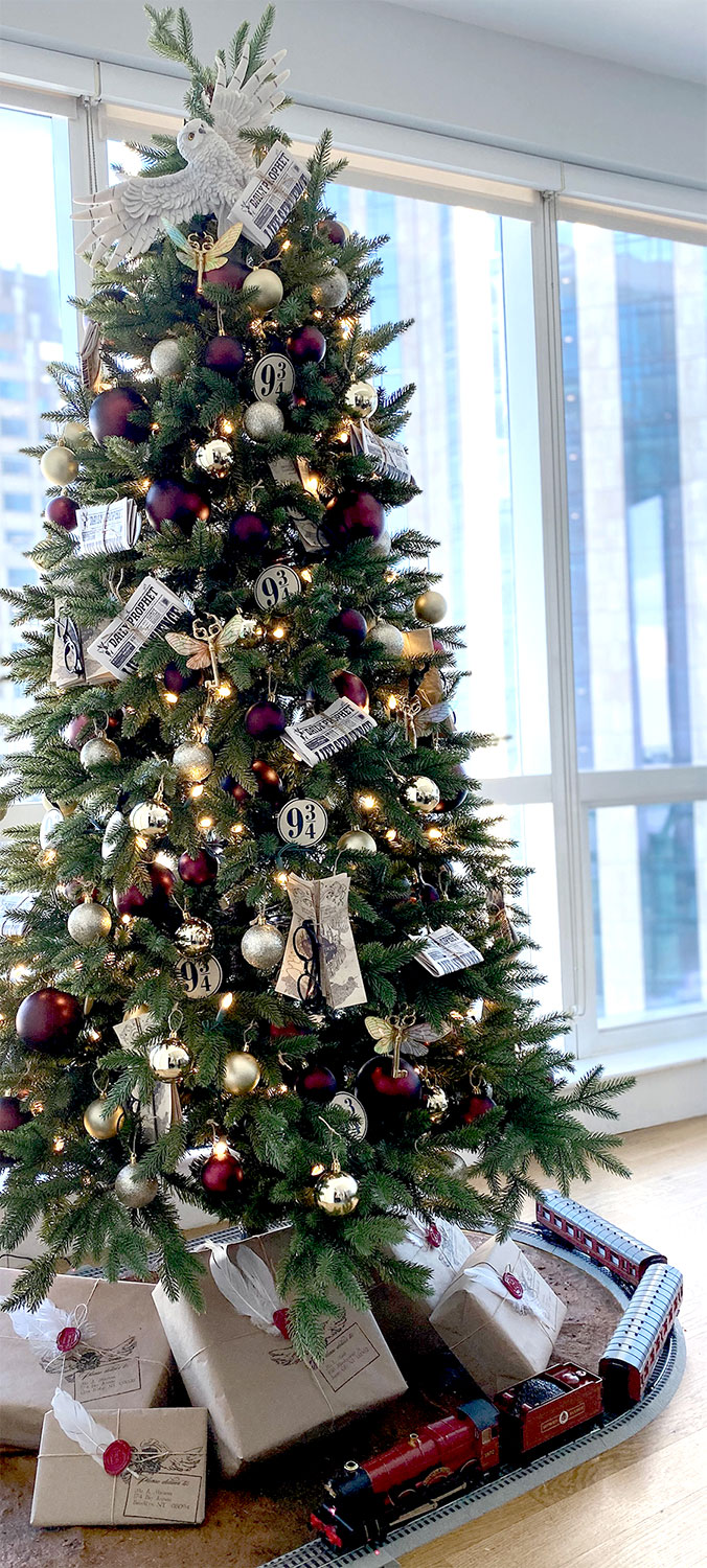 a fantastic elegant Harry Potter Christmas tree with gold, silver and purple ornaments of various sizes, winged keys, lights, glasses, letters, an owl and platform numbers