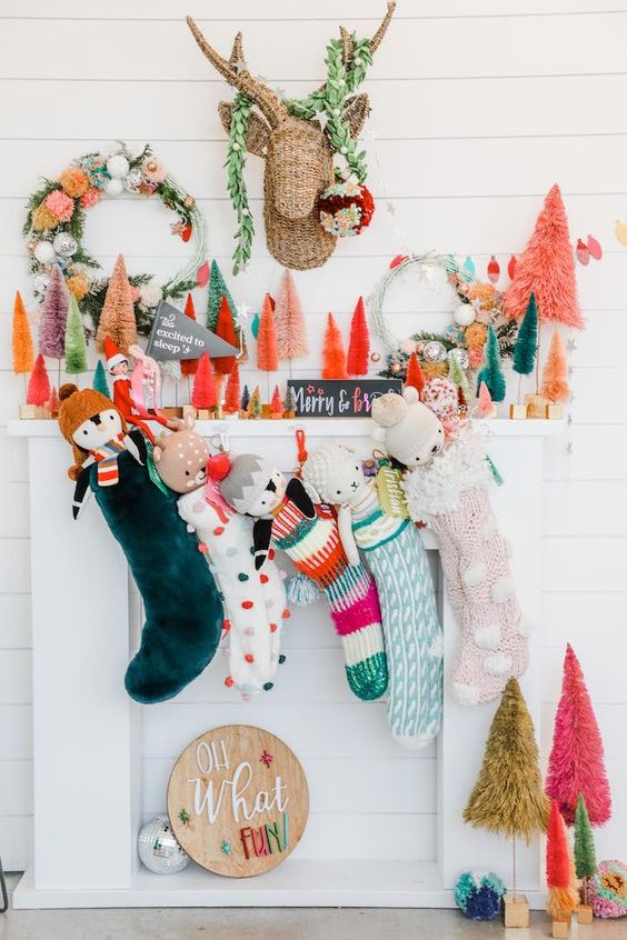 a bright Christmas mantel with colorful bottle brush Christmas trees, a bold wreath, faux greenery and colorful stockings