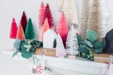 08 a chic Christmas mantel decorated with colorful bottle brush trees, fau greenery, a peppermint garland and mini houses