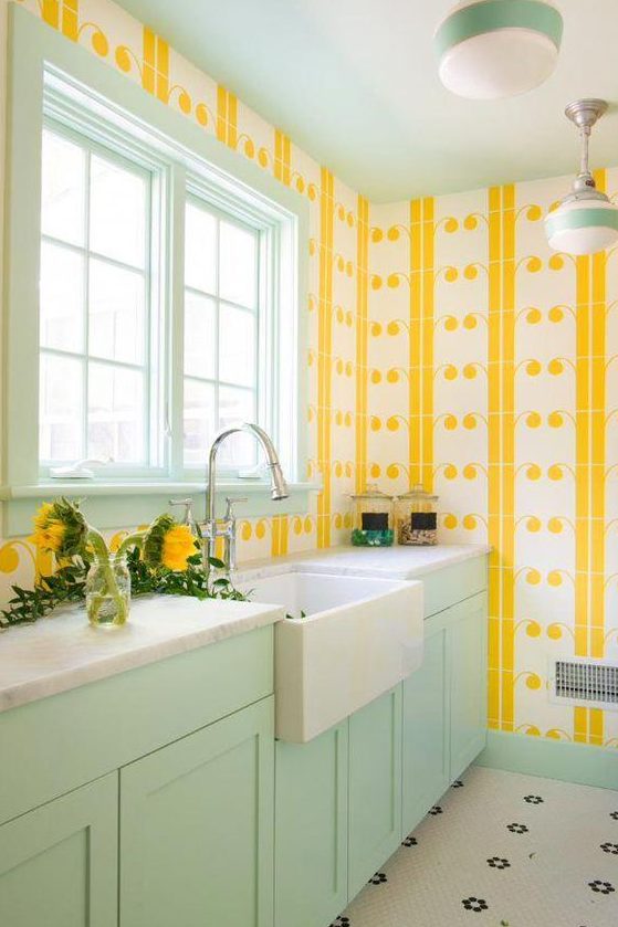 a colorful welcoming kitchen with yellow print wallpaper walls, a mint frame window and mint cabinets for a bold look
