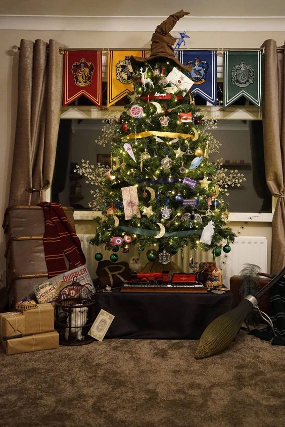 a bright Harry Potter Christmas tree decorated with various ornaments, gilded branches, lights, letters, deer figurines and a Sorting Hat topper