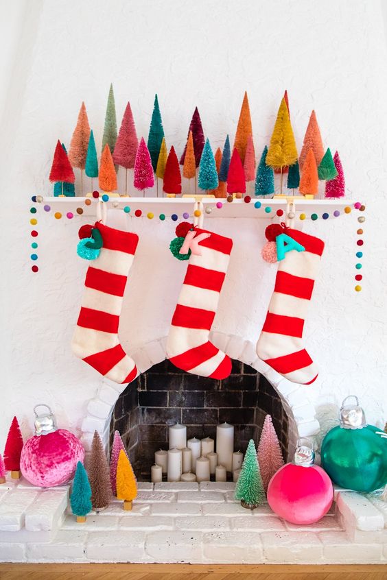 a colorful Christmas mantel with colorful bottle brush trees, a bold felt garland, bright striped stockings with monograms