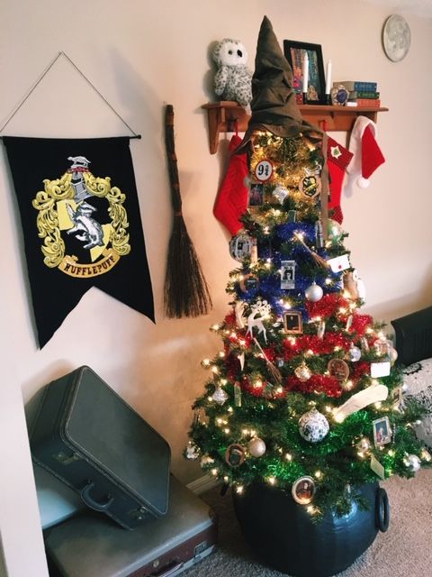a bright Christmas tree decorated with photos, platform numbers, lights, colorful garlands and a Sorting Hat tree topper