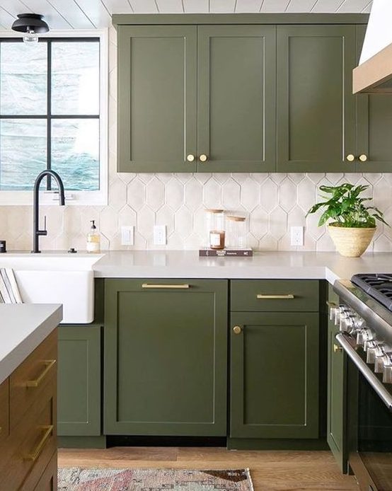 a catchy green kitchen with a white tile backsplash and gold touches plus black fixtures is super stylish