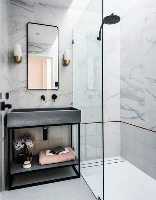 a glam bathroom clad with white marble, with tiles, a concrete sink and black fixtures to give it a fresher modern feel