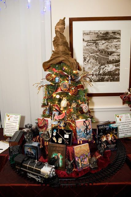 a tabletop Christmas tree decorated with lights, owls and Harry Potter books around plus that famous Sorting Hat on top