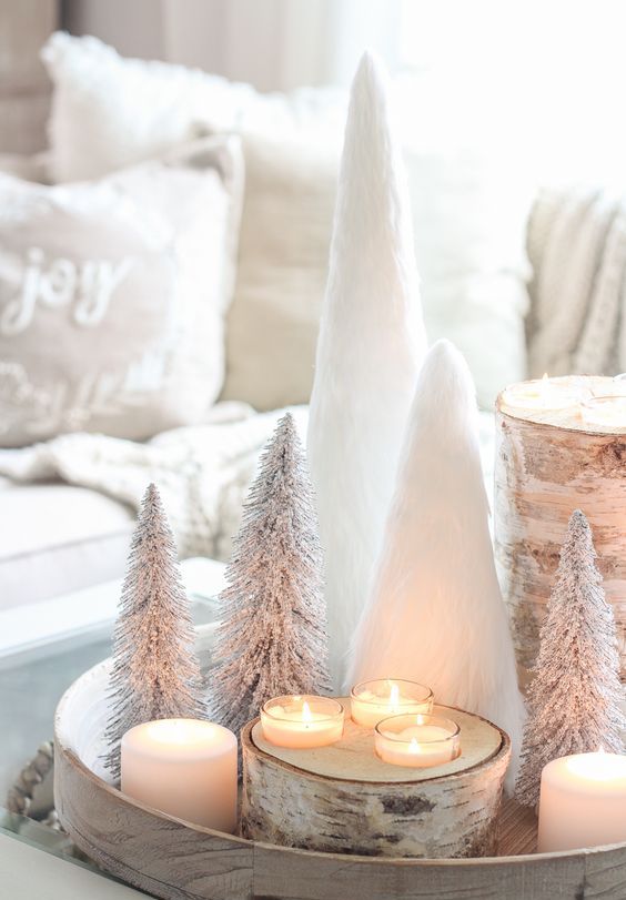 a rustic Christmas arrangement of a wooden tray with candles and birch candleholders, white faux fur and bottle brush trees