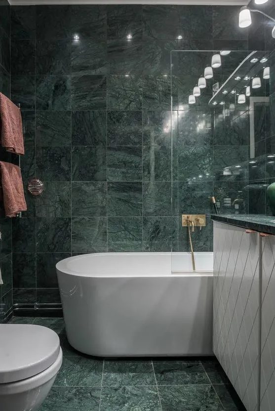 green marble tiles covering the whole bathroom make it a refined and a bit moody space