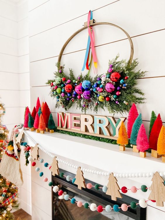 an extra bold Christmas mantel with bright bottle brush trees, letters, a wreath with ornaments and greenery, felt balls and wooden Christmas trees