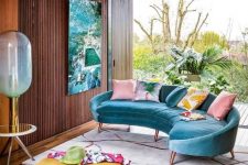 23 a colorful tropical living room with a bright blue curved sofa, a bright yellow flower shaped ottoman and a bold artwork