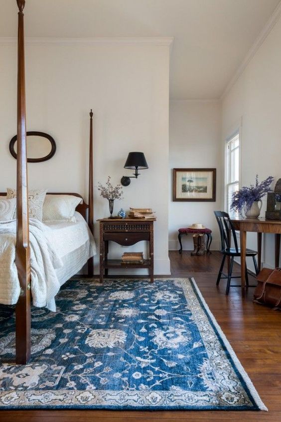 a beautiful vintage bedroom with heavy dark furniture and a bold blue and white printed rug for a touch of color