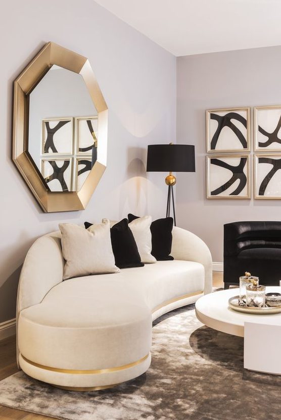 a refined space with a curved white and black sofa, gold touches and bold artworks is an amazing living room