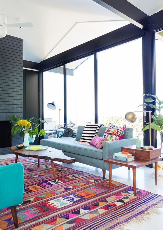 a bold living room with a colorful printed rug that echoes with the pillows and makes the space cooler and bolder