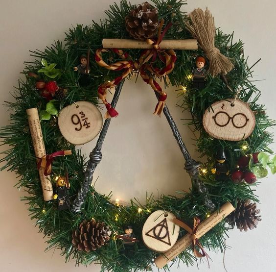 a bright Harry Potter Christmas wreath decorated with pinecones, faux berries, wood slices, letters and lights