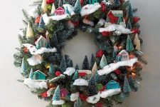 31 a whimsical Christmas wreath decorated with bottle brush trees, colorful little houses and pompoms is pure fun and chic