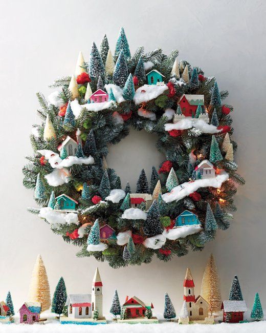 a whimsical Christmas wreath decorated with bottle brush trees, colorful little houses and pompoms is pure fun and chic