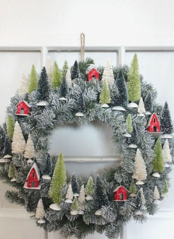 an evergreen Christmas wreath with bottle brush trees and red housesis a lovely idea for holiday decor
