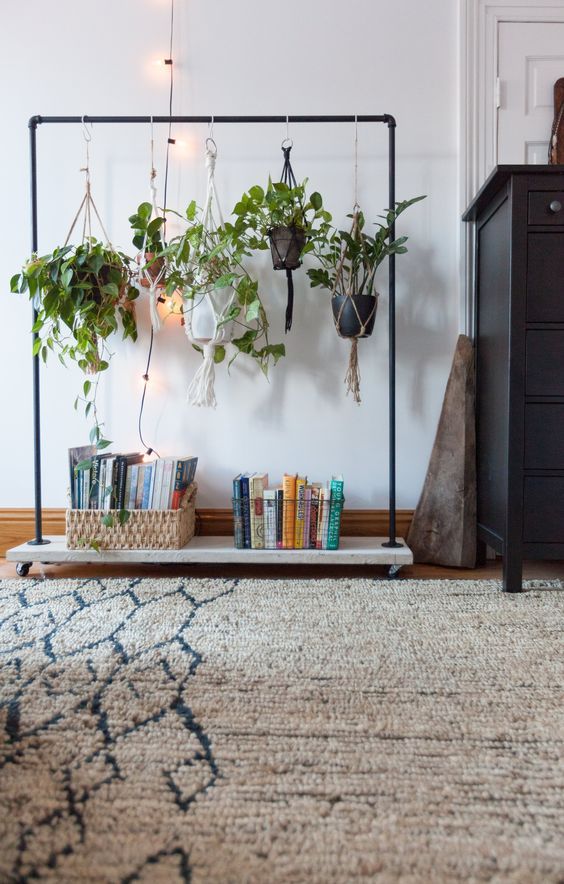 an open frame with lots of hanging potted plants and a couple of baskets with books is a new and fresh storage solution that will keep your room airy