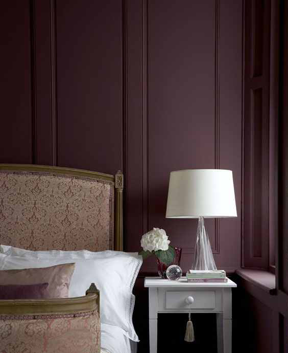a refined and chic bedroom with aubergine walls, a neutral upholstered bed, a vintage nightstand and a lamp is amazing