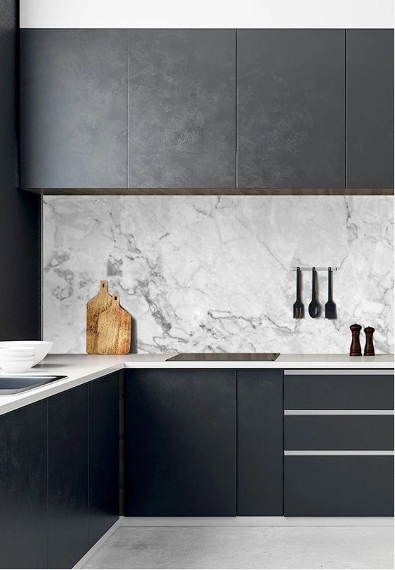 a black minimalist kitchen with sleek cabinets, neutral stoen countertops and a white marble backsplash