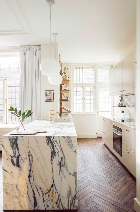 a chic modern kitchen in white and a white marble kitchen island, gold fixtures for a more glam look